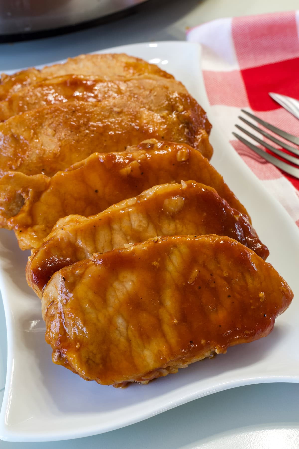 The six cooked pork chops on a white plate ready to be served.