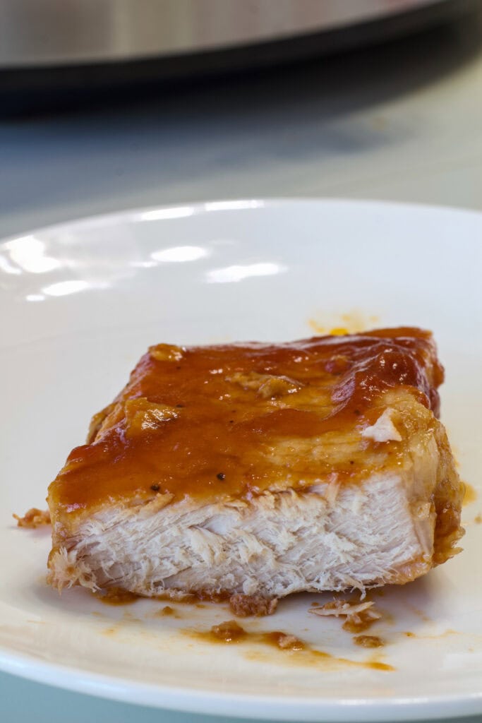 One Crockpot BBQ Cola Pork Chop cut open so the tender and juicy inside is visible.
