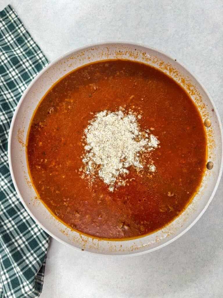 The spice mixture added to the skillet with liquid and ground meat.