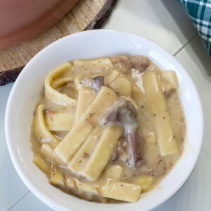 Overhead close up of one serving of Leftover Roast Beef and Noodles in a white bowl.