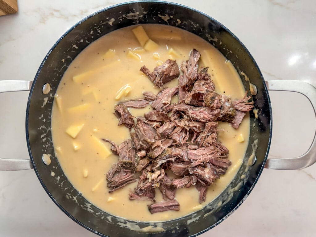 The beef added to the creamy sauce and noodles.