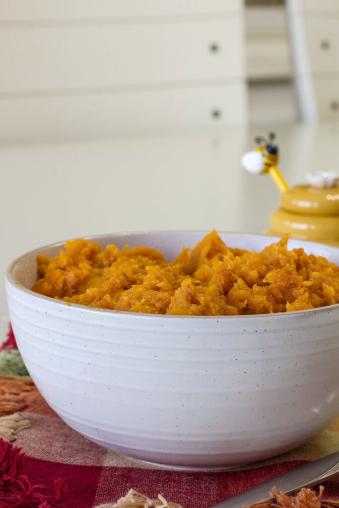 Side shot of the serving bowl filled with Mashed Sweet Potatoes.