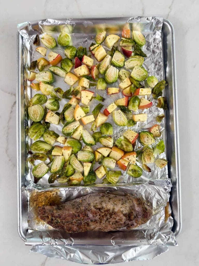 The finished pork, Brussels sprouts and apples on the sheet pan after it came out of the oven.