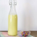Side view of the bottle of homemade Birthday Cake Coffee Creamer and a small bowl of sprinkles.