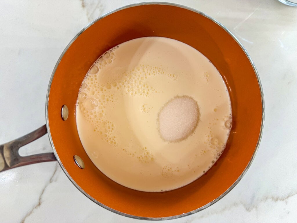 Whole milk, heavy cream and sugar in a small saucepan before being warmed on the stove.