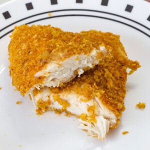 One Crispy Baked Cornflake Chicken Strips that's been cut in half so the inside is visible.