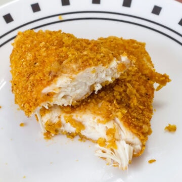 One Crispy Baked Cornflake Chicken Strips that's been cut in half so the inside is visible.