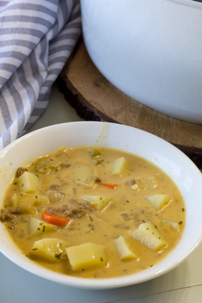 Close up of one serving of Easy Cheeseburger Soup with Dill Pickles in a white bowl.