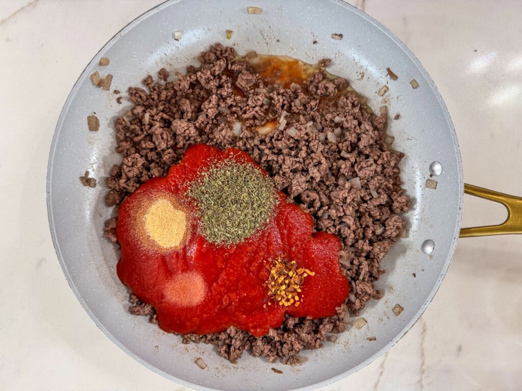 The tomato sauce and herbs and spices added to the ground beef mixture.