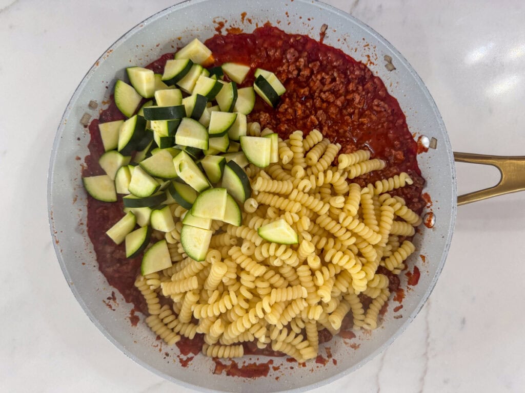The zucchini and cooked pasta added to the skillet.