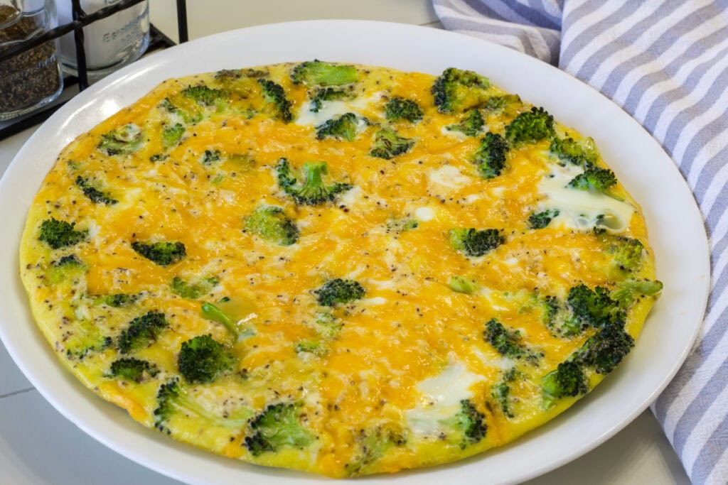 The whole uncut Broccoli and Cheese Frittata on a white plate.