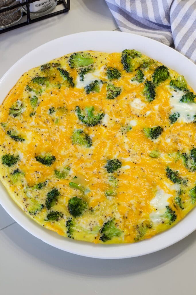 Close up shot of the entire Broccoli and Cheese Frittata on a white plate.