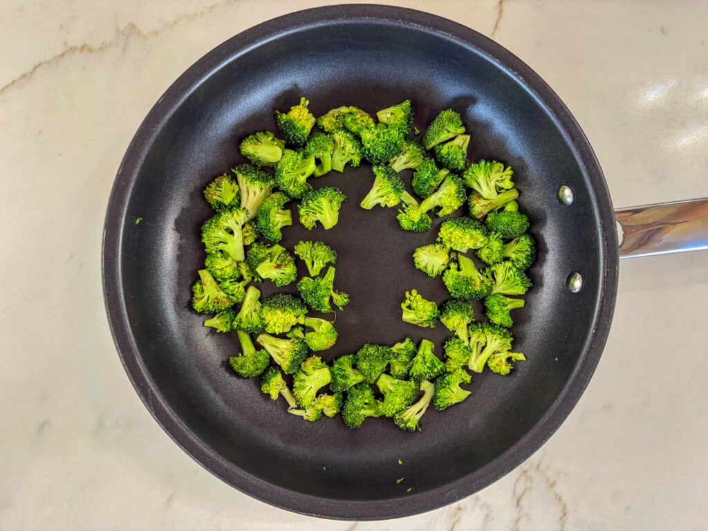 Broccoli florets in the skillet after they've cooked for 5 minutes.