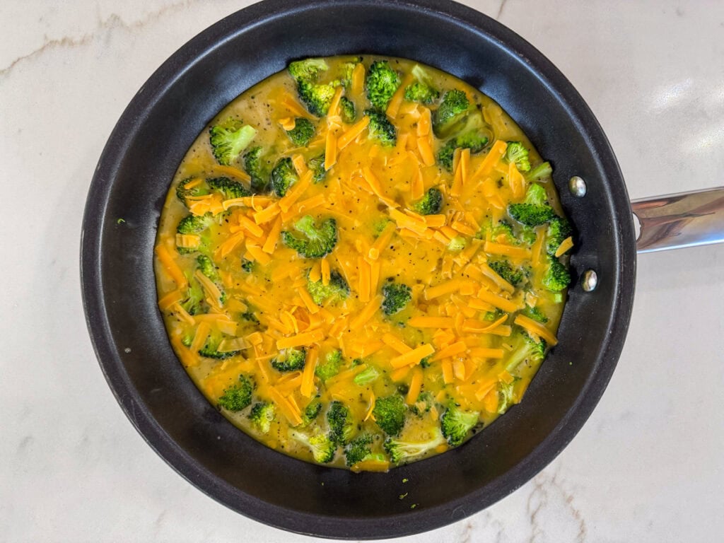 The eggs and cheddar cheese added to the skillet with the broccoli.