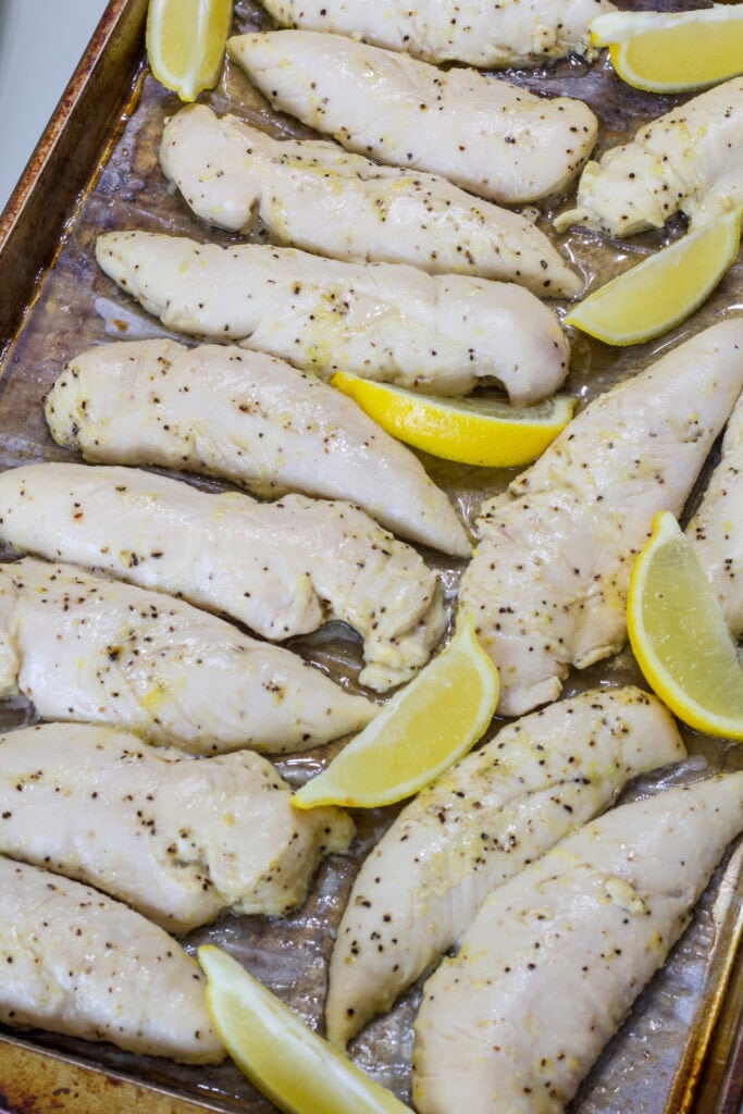 All of the baked Lemon Pepper Chicken Strips on a parchment paper lined rimmed baking sheet.