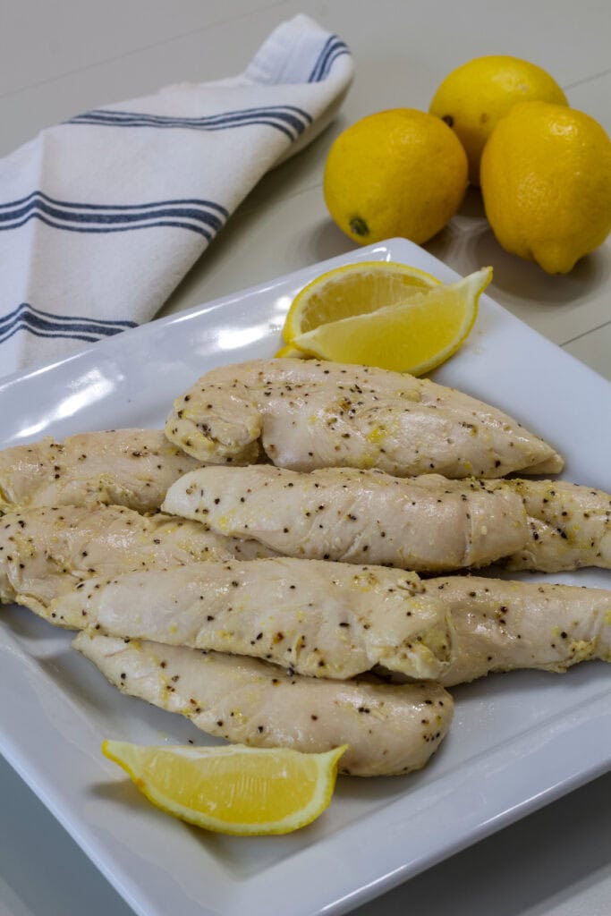 Many Lemon Pepper Chicken Strips on a white serving plate.