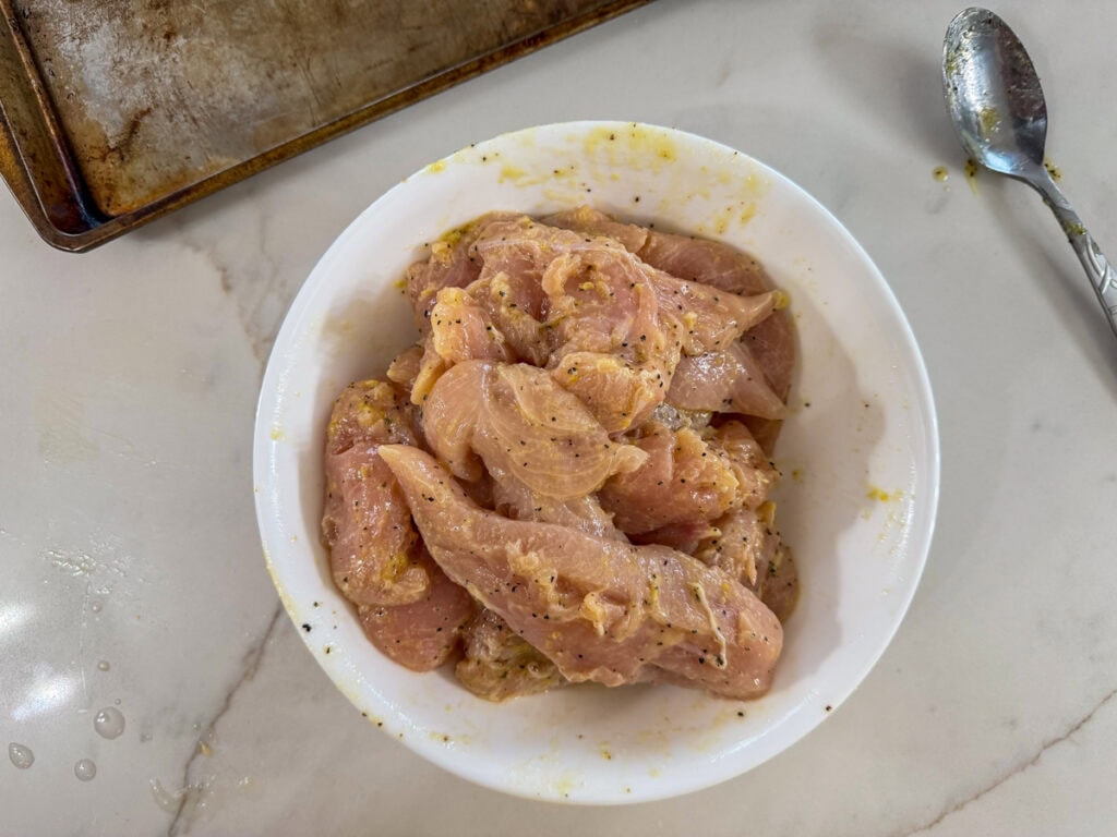 The chicken tenderloins added to the olive oil mixture.