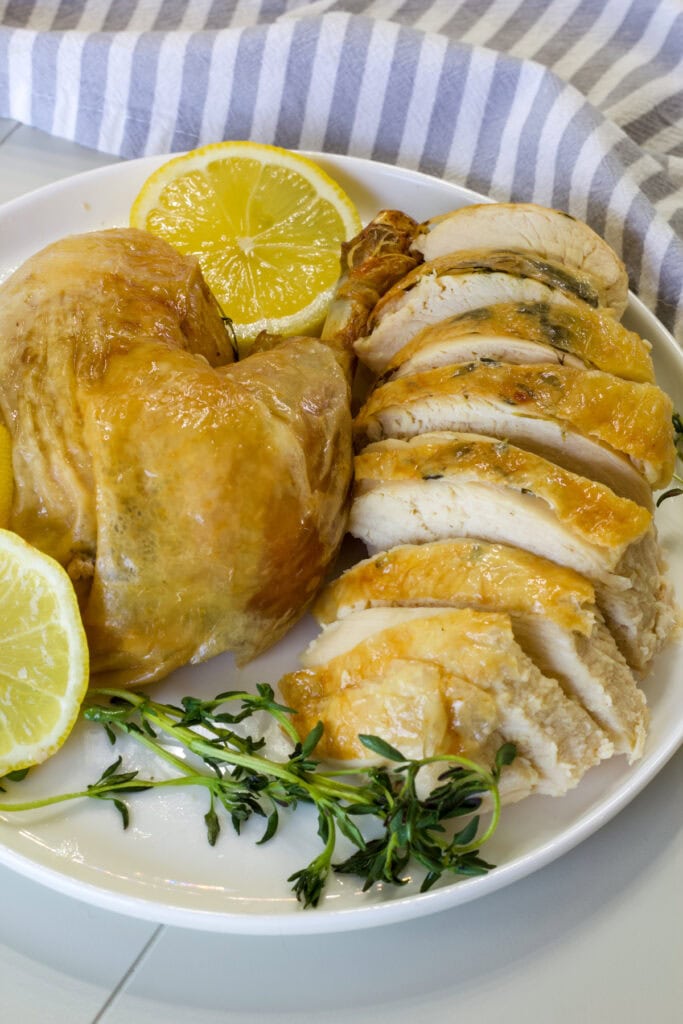 A delicious roasted chicken served with fresh lemon slices and sprigs of thyme, perfect for a flavorful and juicy meal.