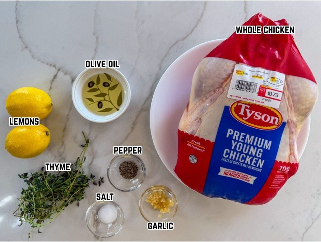 Fresh whole chicken with ingredients including lemons, thyme, garlic, salt, pepper, and olive oil, ready for cooking.