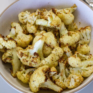 Overhead shot of the golden brown air fryer cauliflower in a round serving bowl.