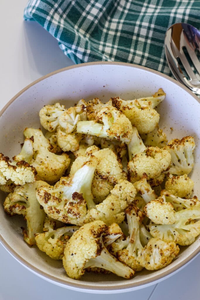 The batch of crispy air fried cauliflower in a cream colored serving bowl.