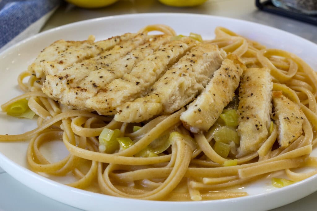 Close up side view of one serving of Lemon Linguine with Chicken on a plate.
