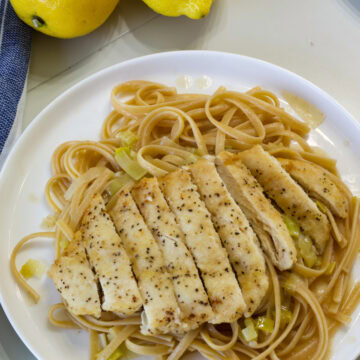 Very close up of one serving of Lemon Linguine with Chicken and leeks on a white plate.