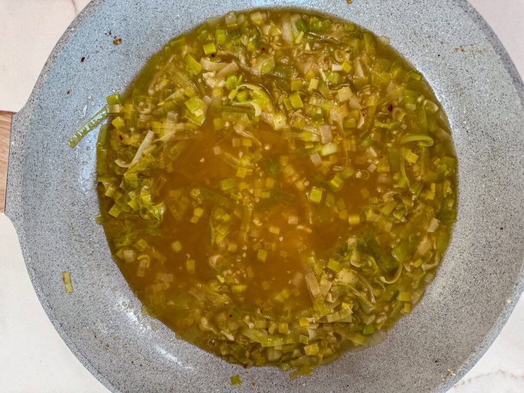 The chicken broth added to the leeks and garlic.