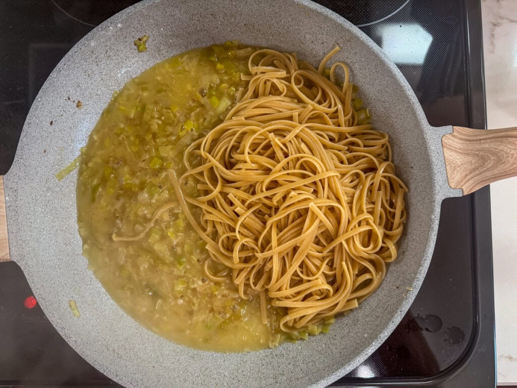 The whole wheat pasta added to the skillet with the leeks, garlic and broth.