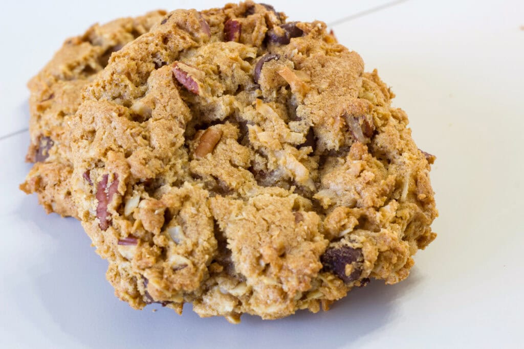 Very close up of two Peanut Butter Cowboy Cookies so the nuts and chocolate chips are visible.
