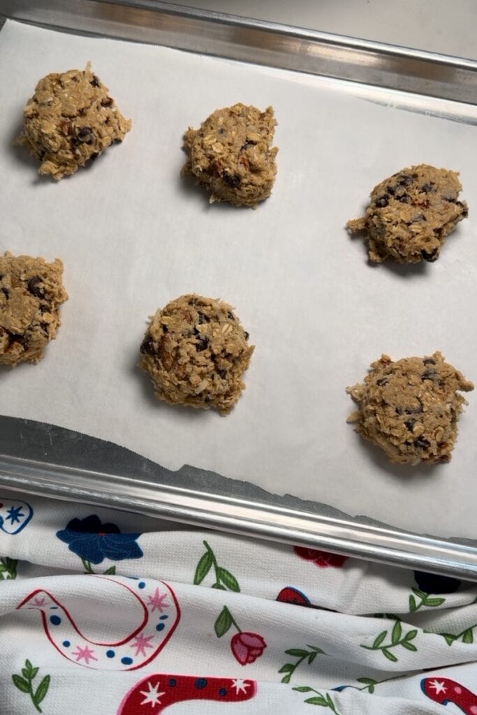 The cookie dough balls on the baking sheet after they've been lightly pressed to flatten them slightly.