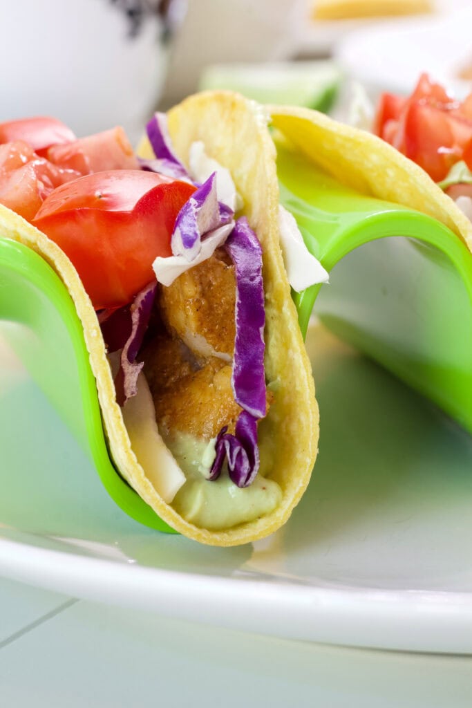 Very close up of one swai fish taco so the avocado cream, fish and toppings are visible.