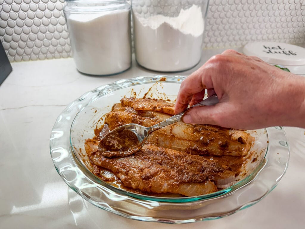 The marinade being spooned over the swai fish fillets.