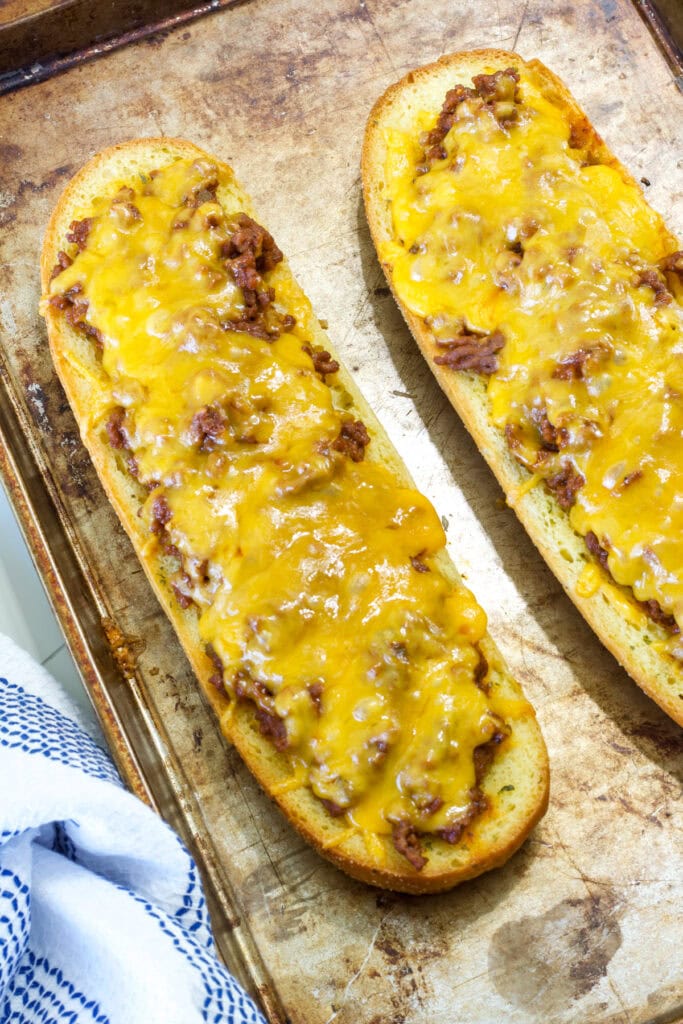 Two finished halves of Sloppy Joe Garlic Bread on a rimmed baking sheet.