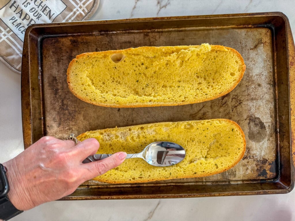 Me making indentations on the baked garlic bread with the back of a spoon.
