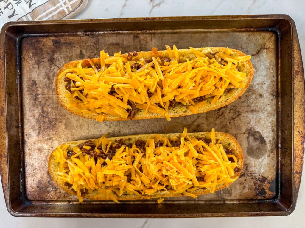 The sloppy joe meat mixture topped with grated cheddar cheese and ready to go into the oven to melt it.