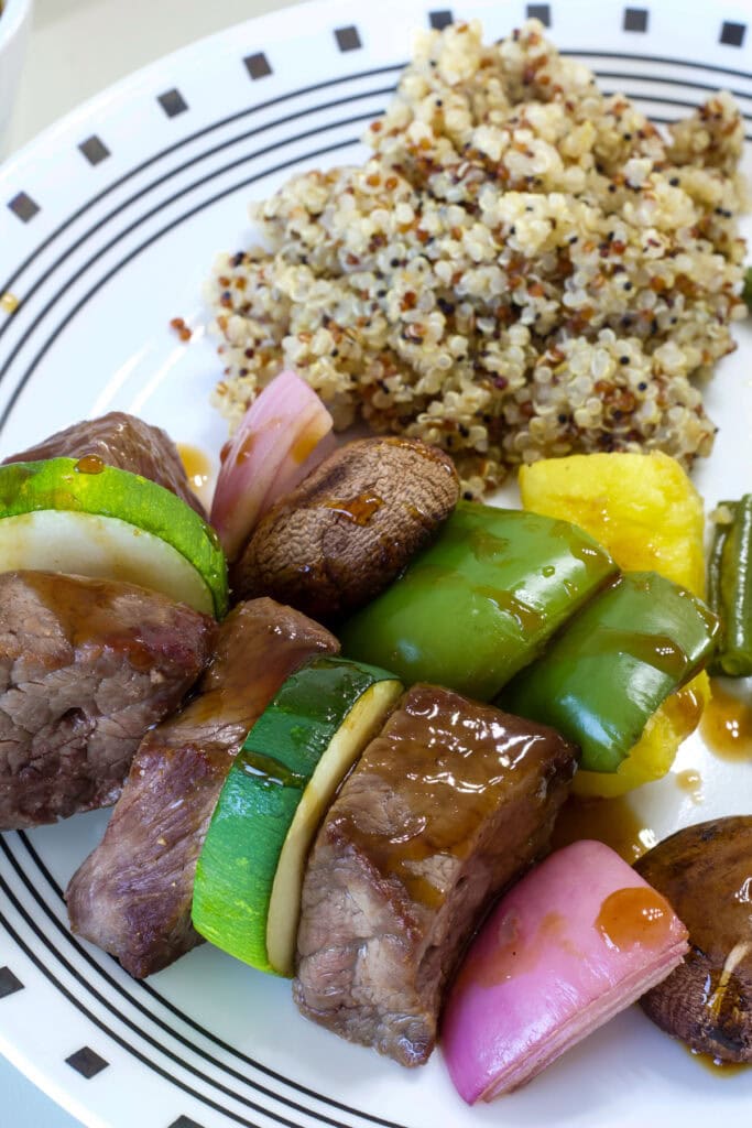 Close up of the cooked beef and vegetables on a plate after being taken off the skewer.