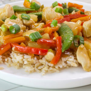 Side close up view of brown rice topped with a serving of Pineapple Chicken Stir Fry.