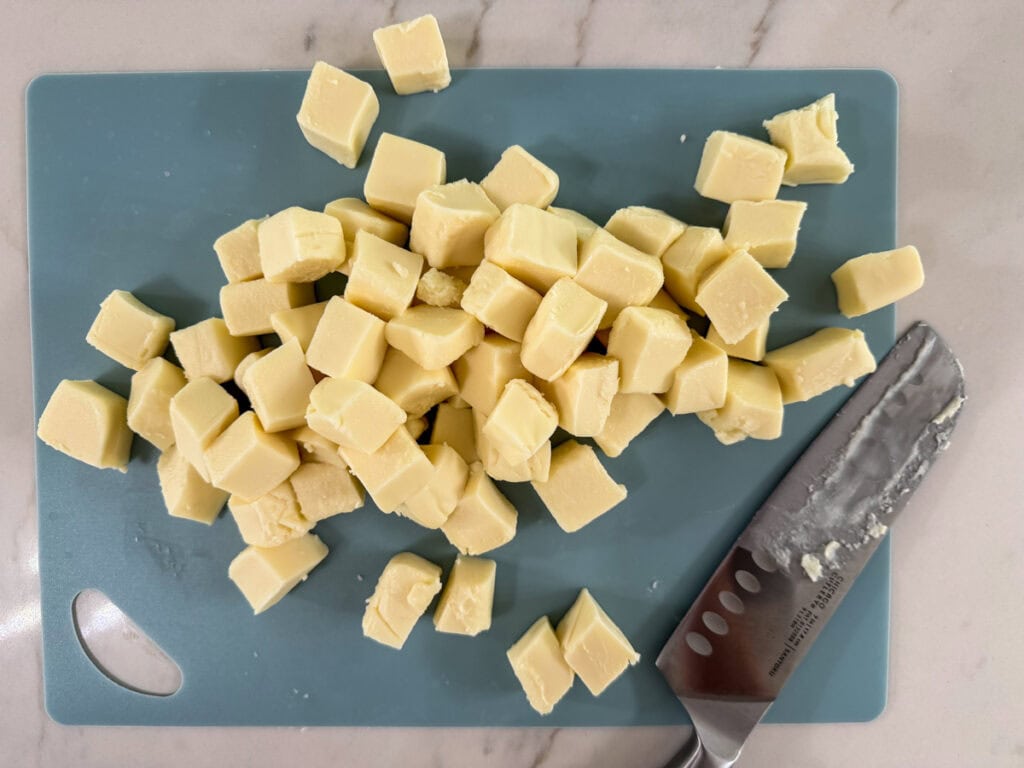 One pound of velveeta queso blanco cut into cubes on a blue cutting boaad.