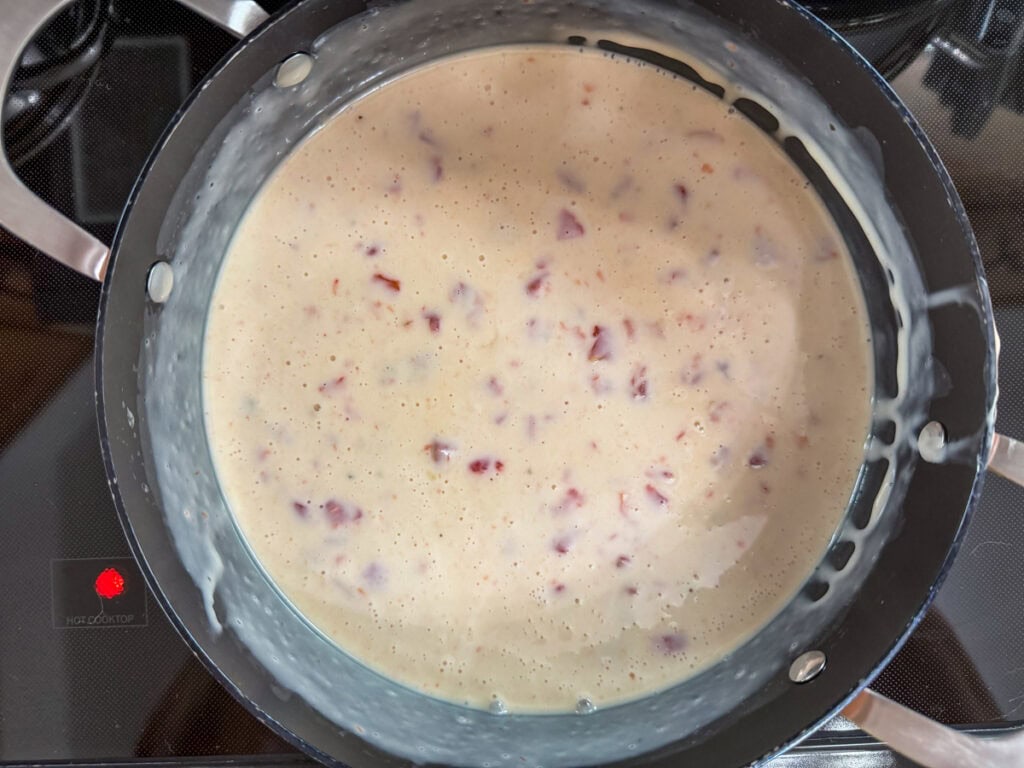The milk, melted cheese and diced tomatoes with green chiles mixed together in a dutch oven.