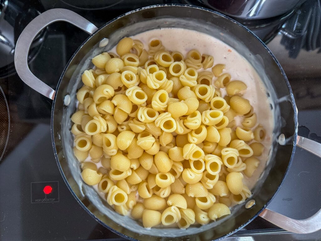 The cooked pasta added to the cheese mixture before being mixed up.