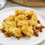 close up of one serving of tater tot casserole so the melty cheese is visible