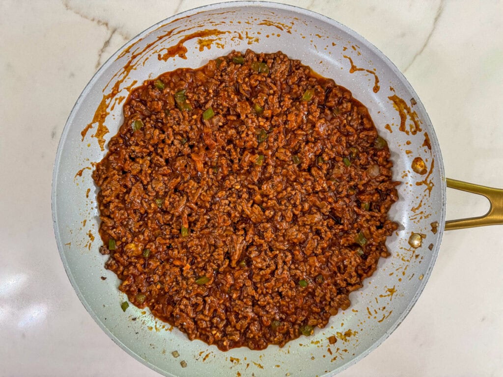 the cooked sloppy joe mixture smoothed out in the bottom of the skillet