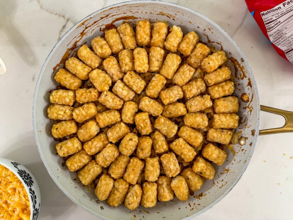 the tater tots arranged on top of the sloppy joe mixture