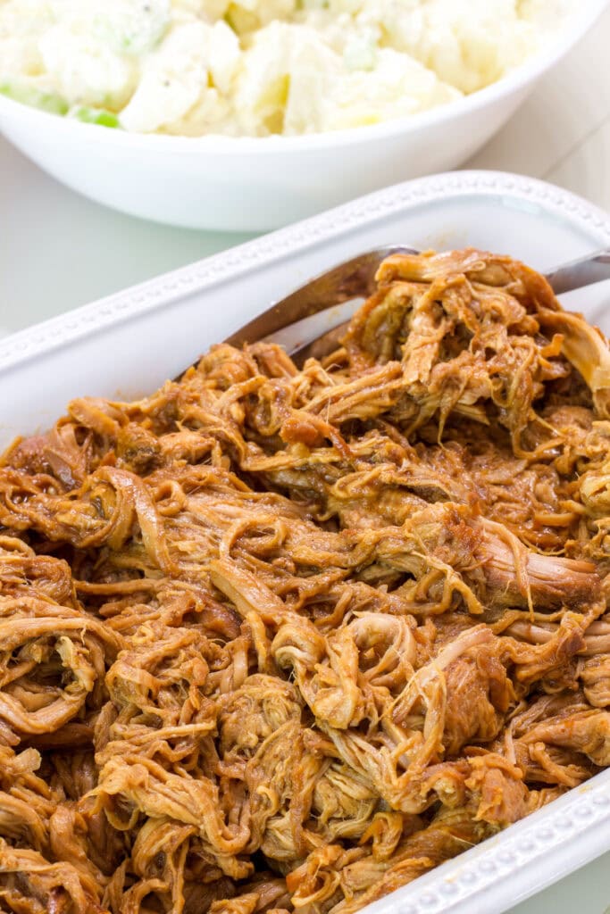 A white rectangle serving dish with the batch of slow cooker pulled pork tenderloin in it.