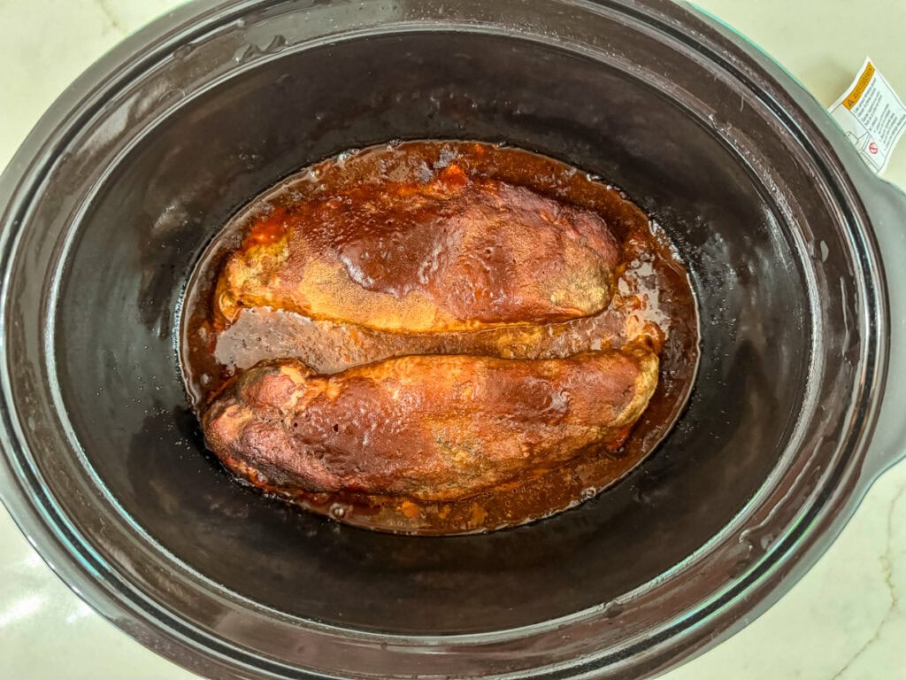 The cooked pork tenderloins in the crock pot.