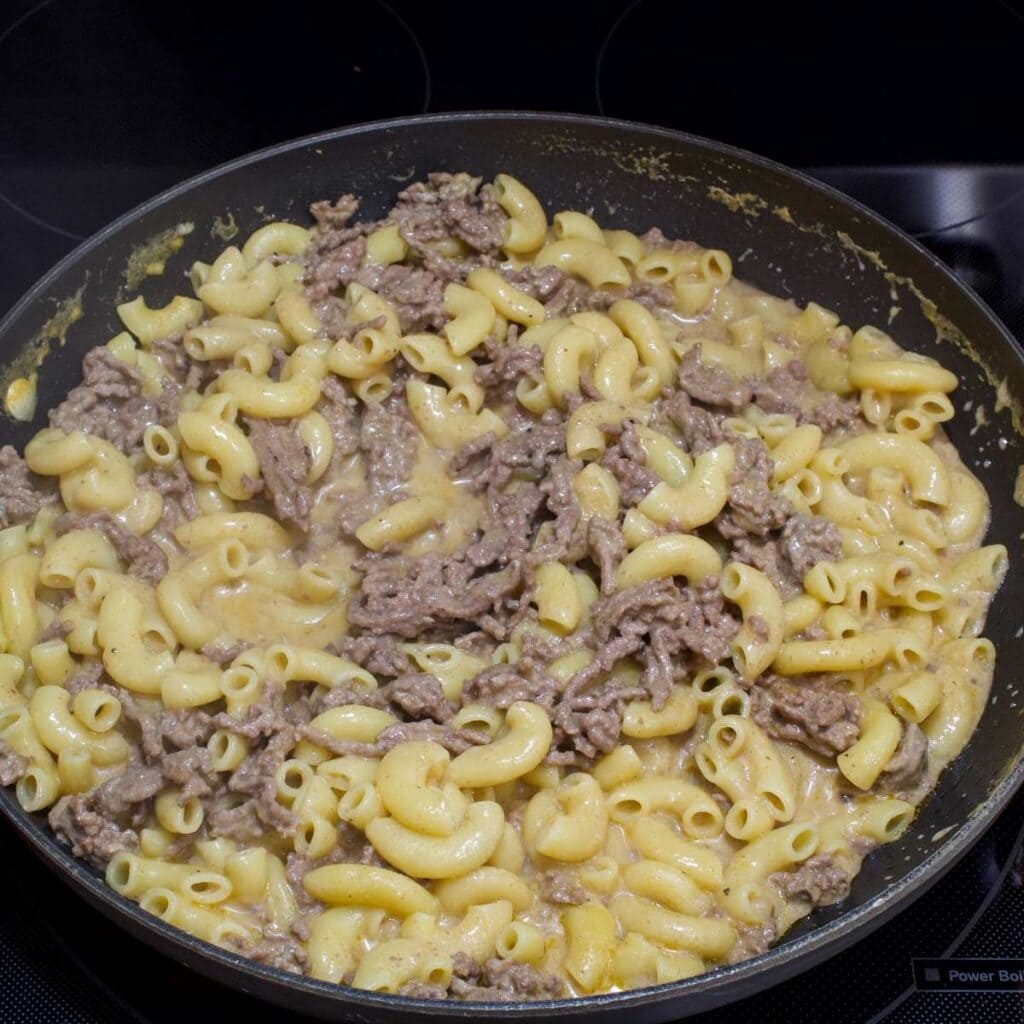 The cheeseburger macaroni in the skillet after being cooked, before the cheese has been added.