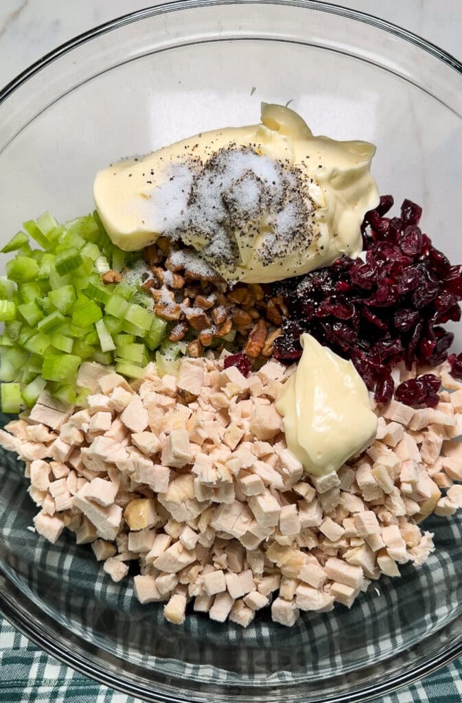 The diced chicken, celery, dried cranberries, pecans, mayonnaise salt and pepper in a large glass mixing bowl.