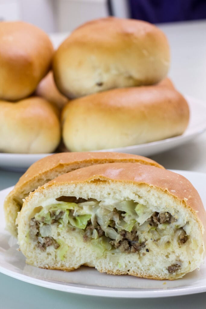 One bierock with provolone cheese cut open so the beef and cabbage filling is visible.