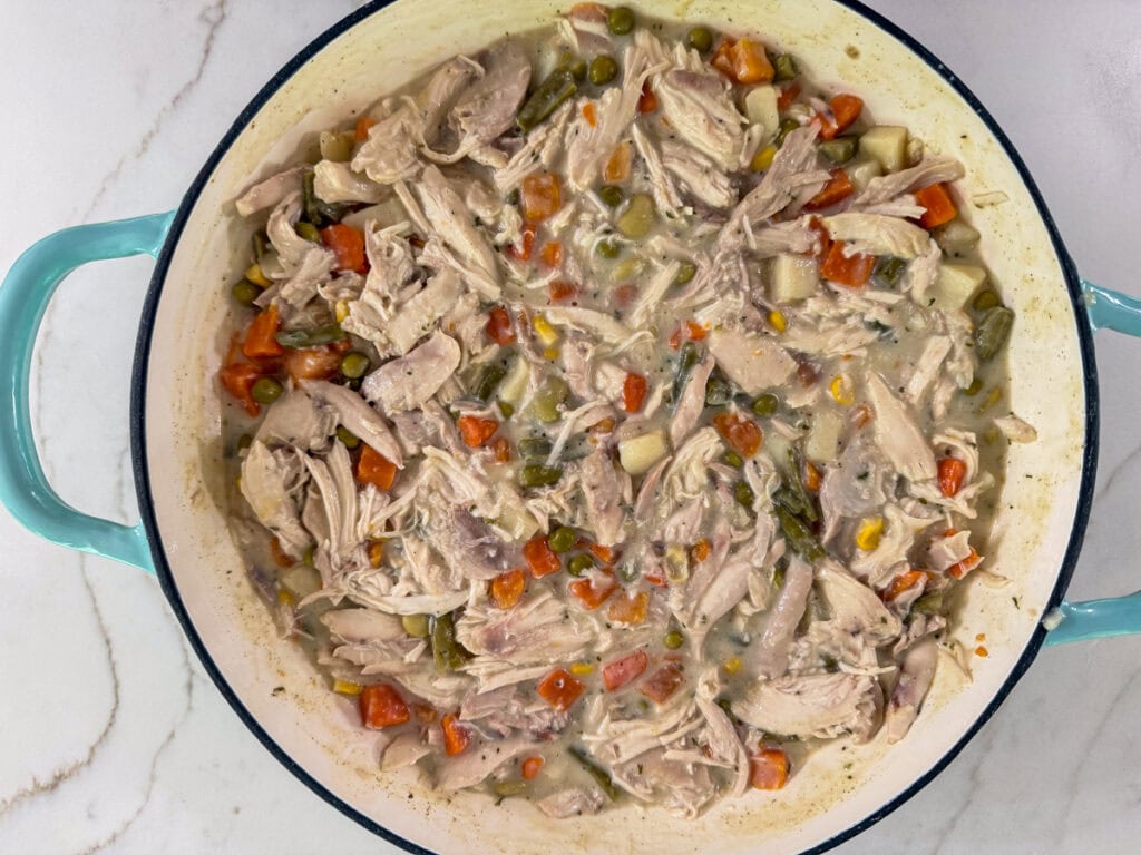 The chicken and vegetables mixed into the sauce in a a skillet.